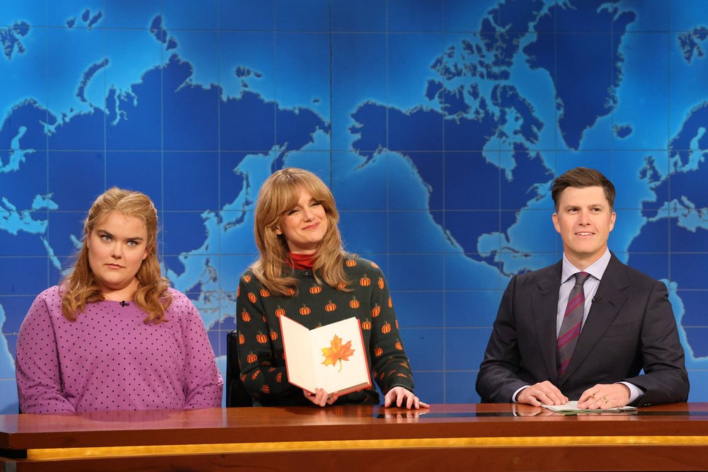 Grace Reiter as Coco, Ashley Padilla as a mom, and Colin Jost at the SNL Weekend Update desk